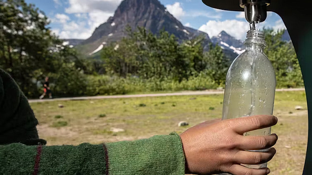 Eine Person, die eine Trinkwasserflasche an einem Außenzapfhahn nachfüllt