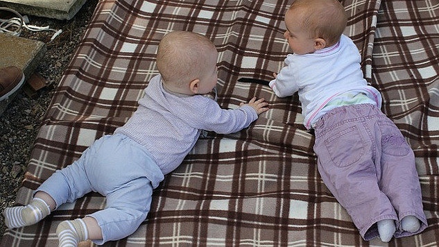 दो बच्चे कंबल पर बातचीत कर रहे हैं