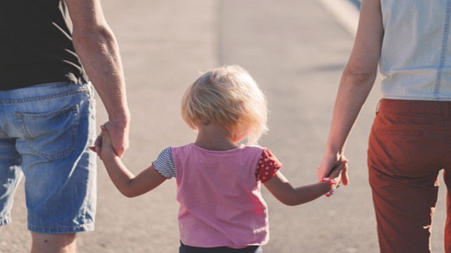 a child holding hands with her parents - one on each side