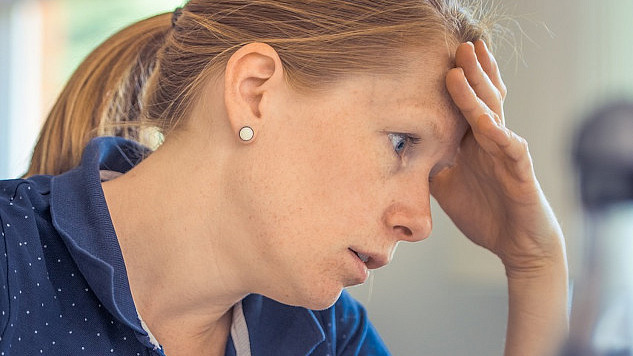 a woman in concentration resting her forehead on her hand