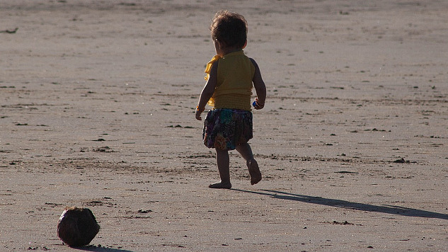 un bambino molto piccolo, solo su una spiaggia