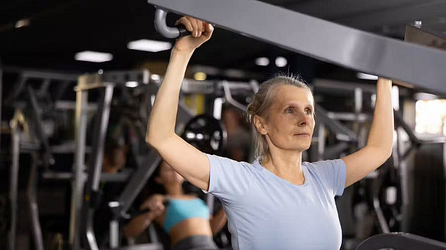 Woman uses weights at the gym to build strength and prevent muscle loss.