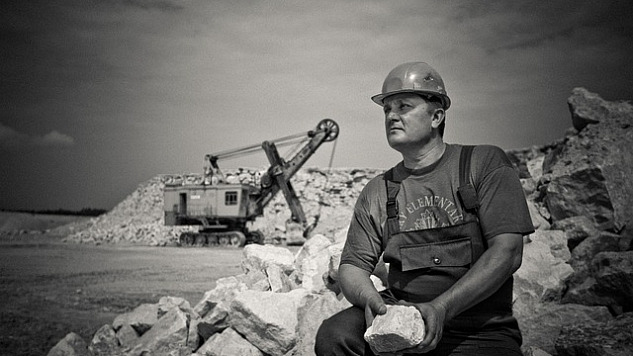 Mann sitzt mit einem großen Stein auf einer Baustelle