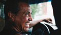 un gioioso uomo sorridente al volante di un'auto