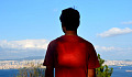 jonge man met een hart dat licht uitstraalt staat op een heuvel met uitzicht op een stad