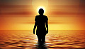 kvinna som står i havet och tittar på den uppgående solen
