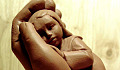 uma escultura de argila de uma criança sendo segurada por uma mão de apoio