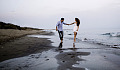 lelaki dan wanita berjalan di pantai berpegangan tangan