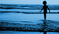 мальчик стоит в воде на краю волн, колеблющихся по воде