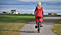 seorang wanita senior berambut putih dan berpakaian merah menunggang basikal