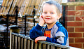 seorang anak laki-laki berdiri di pagar dengan damai memandang ke luar