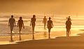 ihmiset kävelevät paljain jaloin veden äärellä rannalla