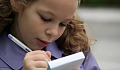 uma jovem escrevendo atentamente em um bloco de papel