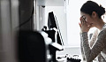 μια γυναίκα σε έναν υπολογιστή με τα χέρια της να καλύπτουν το πρόσωπό της