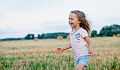 радостный маленький ребенок бежит по полю