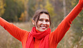 улыбающаяся молодая женщина, одетая в красное, с поднятыми руками в знак победы