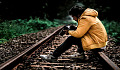 молодой человек сидит на железнодорожных путях