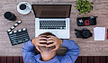 man sitting in front of his laptop with his hands behind his head