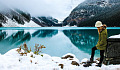 湖の隣の雪の中に立つ若い女性
