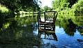 una sedia di vimini nelle acque calme di un fiume vicino alla riva