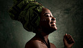 Afrikanische Frau, die eine Kopfbedeckung mit geschlossenen Augen trägt und lächelt