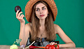 एक महिला अपने सामने ताज़ी सब्जियों की एक श्रृंखला और एक एवोकैडो पकड़े हुए है