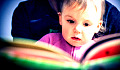 کودکی که روی بغل مادرش نشسته و از روی کتاب می خواند
