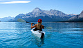 mujer joven en kayak en un lago rodeado de montañas