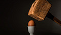 एक अंडे के ऊपर एक भारी हथौड़ा रखा जा रहा है