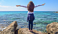 gadis muda dengan tangan terbuka lebar di depan laut