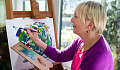 一个女人抱着一个调色板，并在绘画上工作