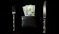 una tavola apparecchiata con coltello e forchetta e un portafoglio pieno di soldi dove di solito sarebbe il piatto