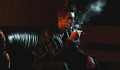 ung mand sidder i mørke omgivelser og ryger