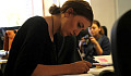 ung kvinna sitter vid ett skrivbord i djup koncentration