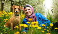 kvinne og hund som legger seg i et felt med ville blomster