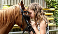 en ung flicka som lutar sitt ansikte mot en hästs panna