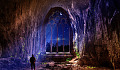 a man in a cave with a huge arch opening to the night and sky