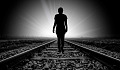 silhouette d'une personne marchant sur une voie ferrée vers la lumière