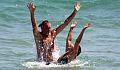 ,man and woman in the ocean with hands up in the air in joy