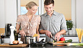 un uomo e una donna che preparano il cibo insieme in cucina