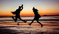 dos personas saltando de alegría en la playa