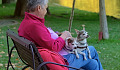 una donna dai capelli bianchi seduta fuori con due cagnolini in grembo