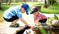 two young boys playing on the edge of a pond