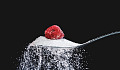 a raspberry sitting on top of a teaspoon of sugar