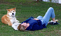 seorang wanita berbaring di rumput bersama anjingnya