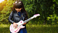 gadis muda dengan bunga di rambutnya memainkan gitar listrik