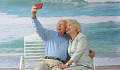 starsza, siwowłosa para siedząca na ławce na plaży robiąca selfie