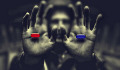 Pria dalam bayang-bayang memegang pil merah di satu tangan dan pil biru di tangan lainnya