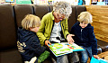 một người bà đang đọc cho hai đứa cháu của mình nghe
