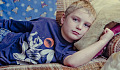 ung gutt som ser grinete ut som ligger på sofaen